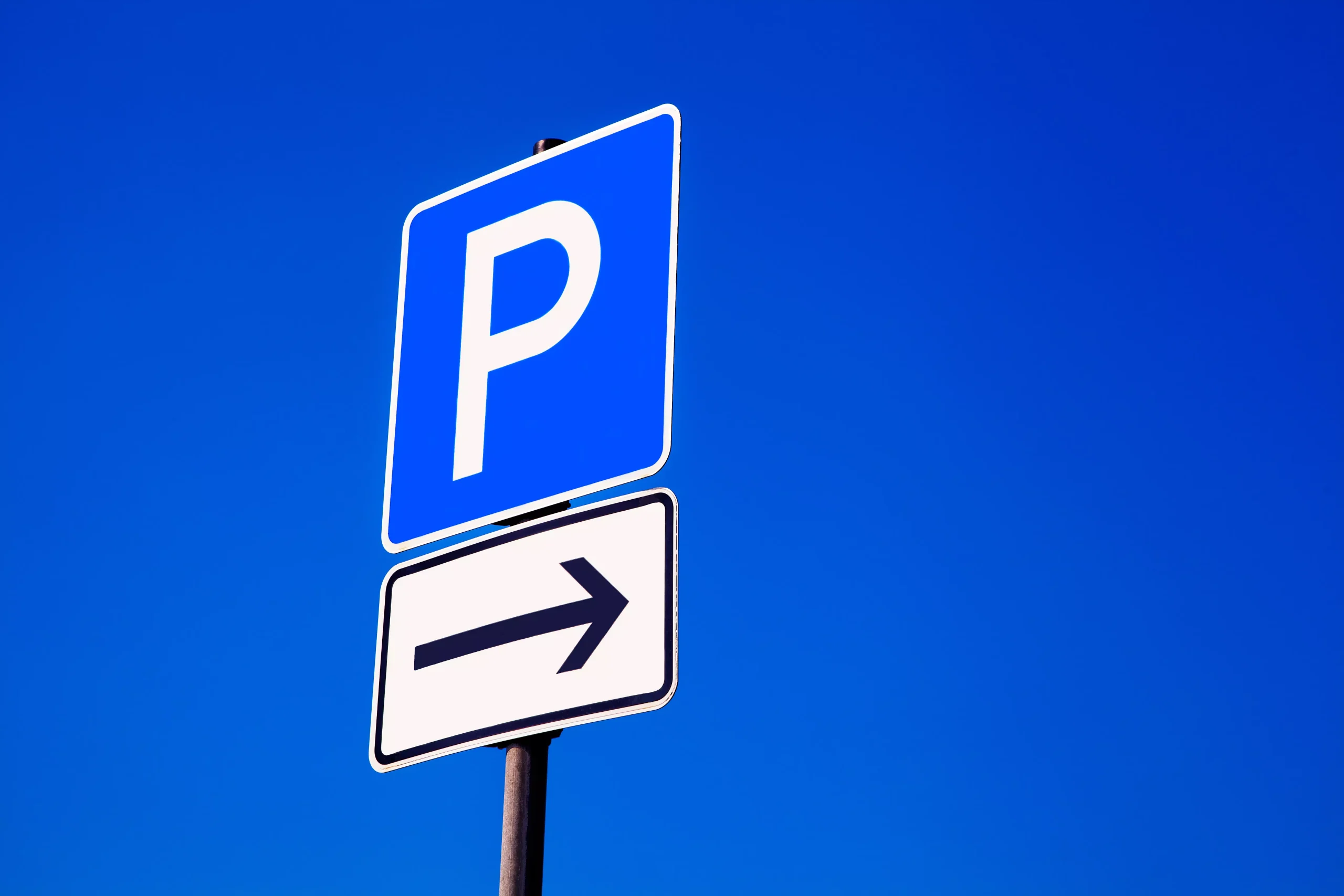 Parkplatzschild mit einem Richtungspfeil darunter
