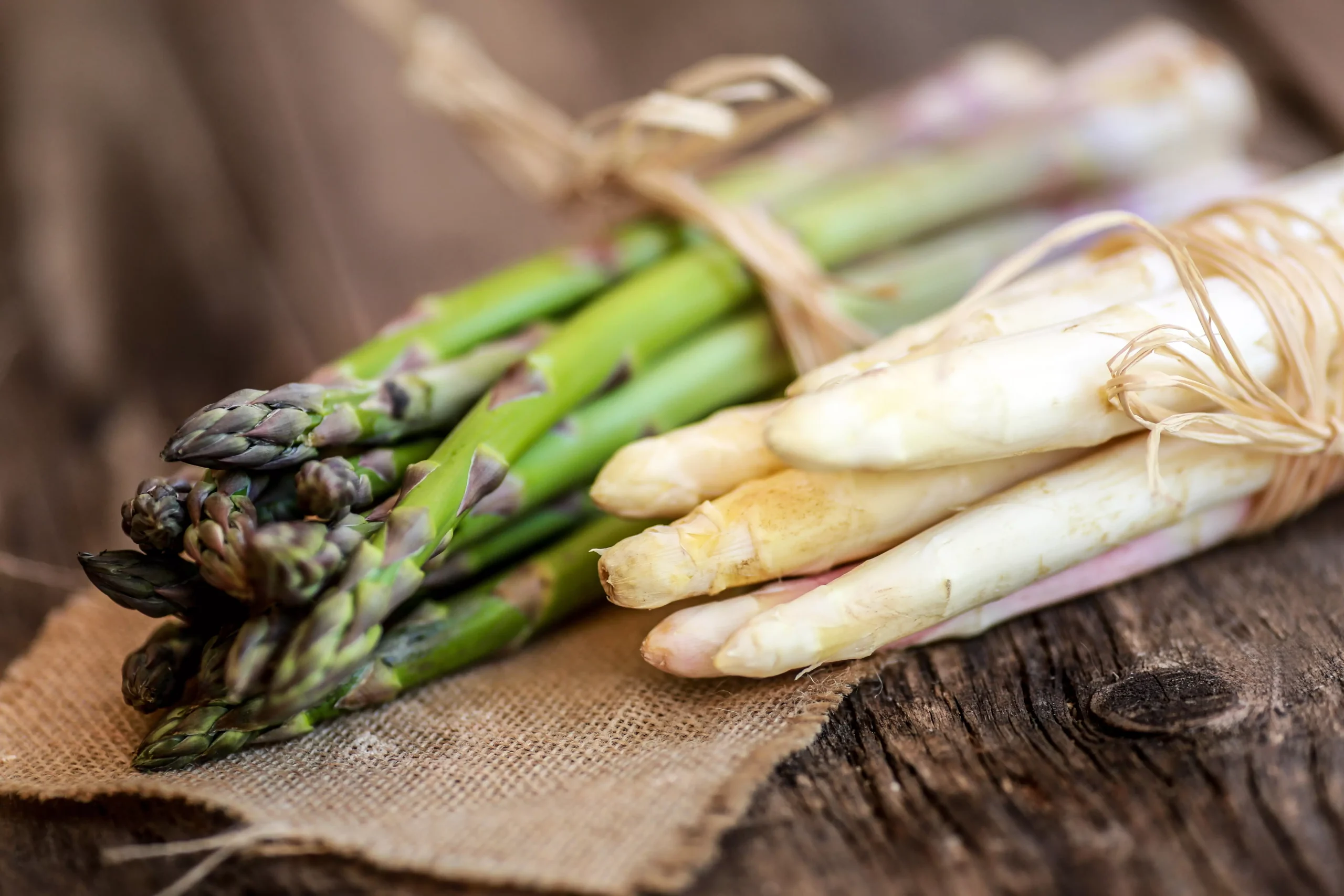 Grüner und weisser Spargel auf einem Holzbrett platziert